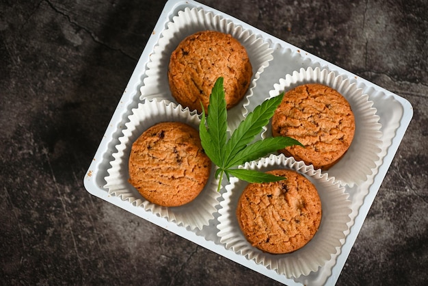 Cannabis food cookies box with cannabis leaf marijuana herb on dark background delicious sweet dessert cookie with hemp leaf plant THC CBD herbs food snack and medical concept