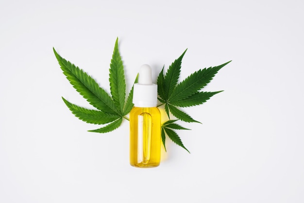 Cannabis oil and hemp leaf on white background flat lay Hemp CBD oil for skin care