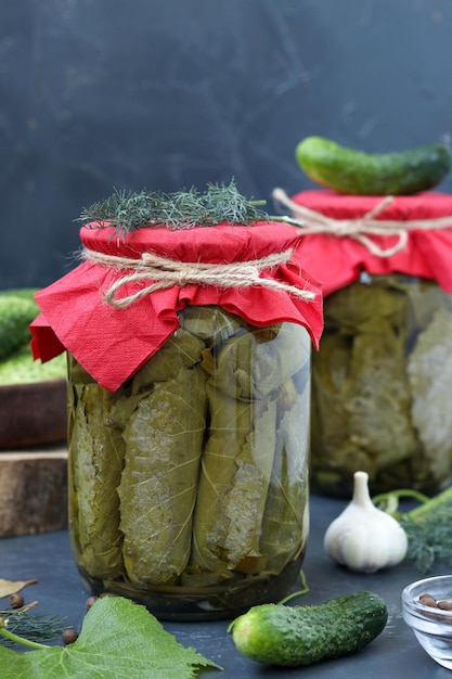 Canned cucumbers in grape leaves in glass jars on a dark background Harvest for the winter