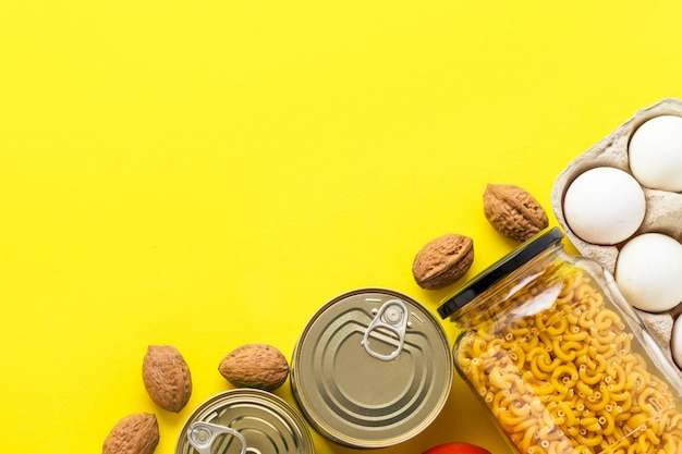 Canned goods, walnuts, fresh vegetables, tomato and cucumber, chichen eggs and pasta in glass jar on pink background