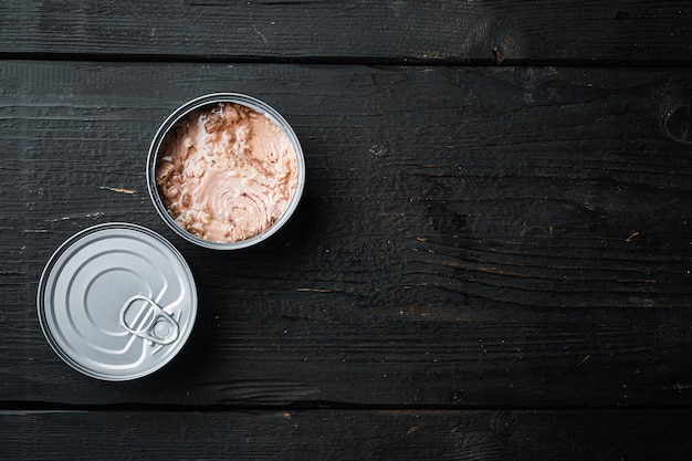 Photo canned italian tuna set, in tin can, on black wooden table