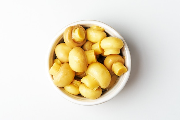 Canned mushrooms in a bowl on a white background. Top view. 
