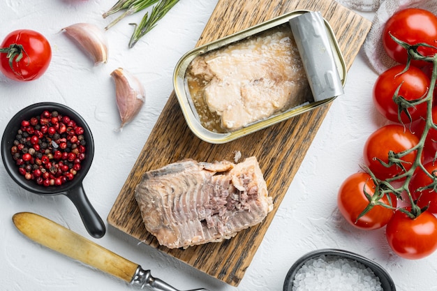 Canned Wild Pink Salmon set, on wooden cutting board, on white table with herbs and ingredients, top view flat lay