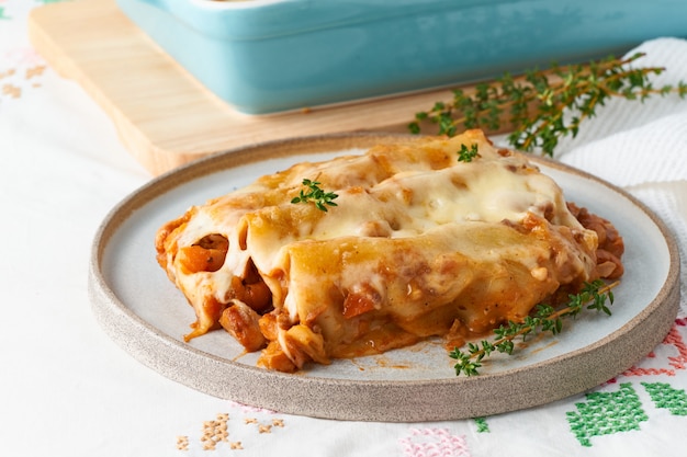 Cannelloni pasta with filling of ground beef, tomatoes, baked with bechamel tomato sauce