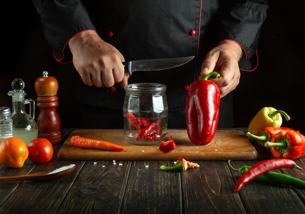 Canning peppers in a jar with spices A chef prepares capsicum in a restaurant kitchen