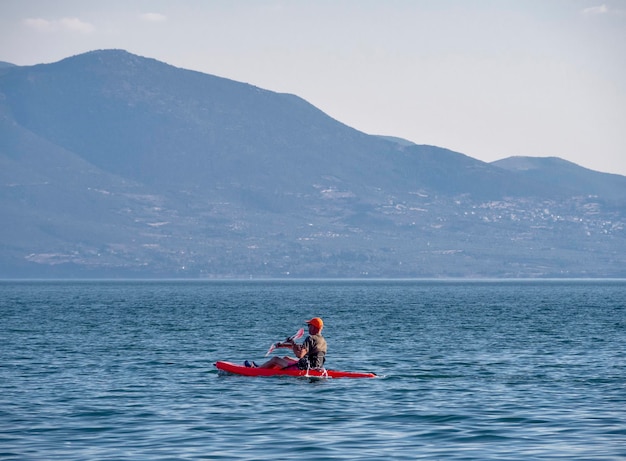 Canoeists go by canoe in the Aegean Sea on a background of a cliff in Greece on a sunny day