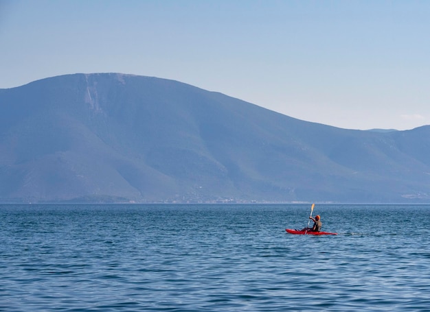 Canoeists go by canoe in the Aegean Sea on a background of a cliff in Greece on a sunny day