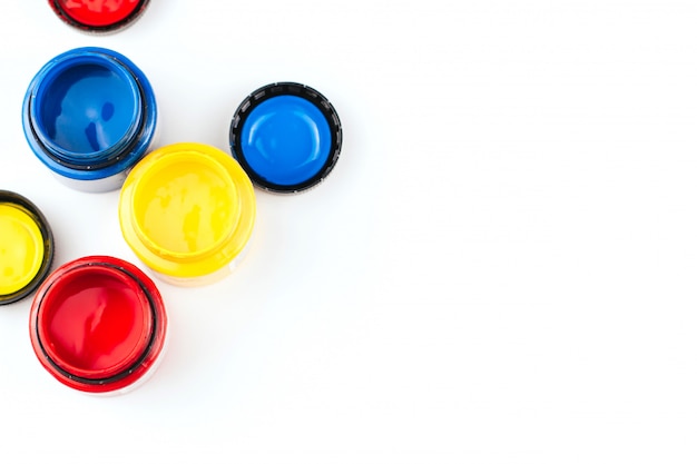 Cans of acrylic paint in blue, red and yellow on a white background copy space. Artistic paints.