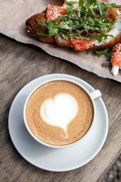 Cappuccino and bun breakfast at the cafe. American morning. Croissant with trout and arugula