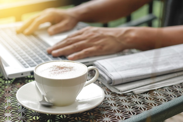 Cappuccino coffee cup with man hands to do list message on notebook