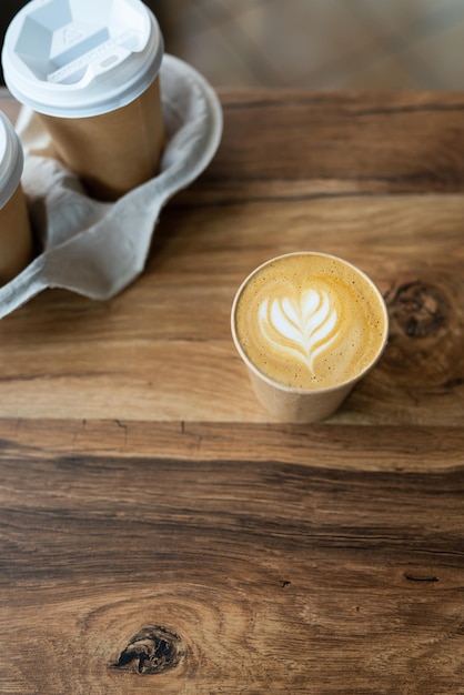 Cappuccino coffee with beautiful pattern on foam in eco craft glass on table favorite coffee cup concept Coffee to go concept