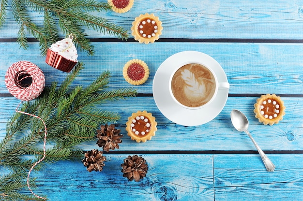 Cappuccino in a Cup and Christmas background  with fir cones, tree branches and cake