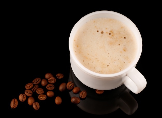 Cappuccino in a cup with foam and coffee beans black background