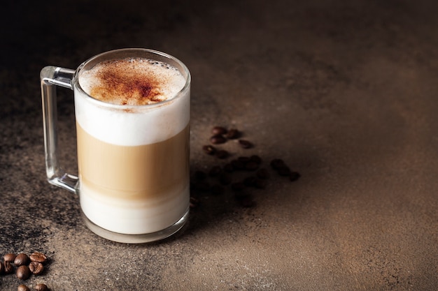 cappuccino in a glass Cup with cinnamon on a dark brown