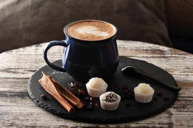 Cappuccino in a mug, cinnamon and cupcakes with cream and chocolate