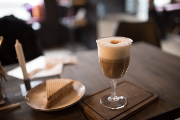 Cappuccino and a slice of cake on a table in a cafe.