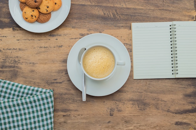 Cappuccino time on wooden table and notebook