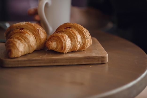 Cappuccino with beautiful latte art and croissant on wooden background on the table. Perfect breacfast in the morning. Rustic style.