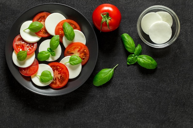 Photo caprese italian antipasto appetizer with ingredients for cooking tomato mozzarella and basil on dark background top viewxa