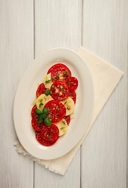 Caprese salad Italian traditional dish tomatoes with mozzarella cheese basil and spices top view no people