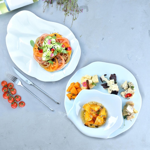 Caprese salad and a set of noble cheeses on a gray table. Italian food. Snacks. Top view