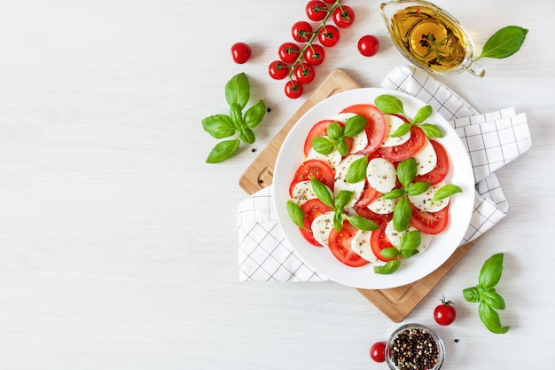 Caprese salad with mozzarela tomatoes fresh olive oil and basil on white background