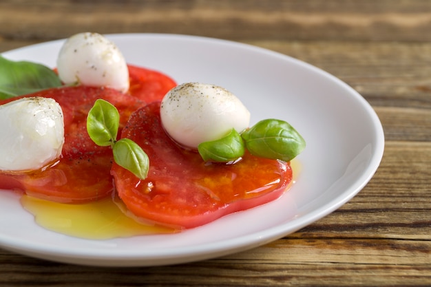 Caprese salad with ripe tomatoes and mozzarella with fresh Basil leaves.