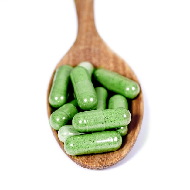 Capsules of Green herbs on spoon healthy eating for healthy living