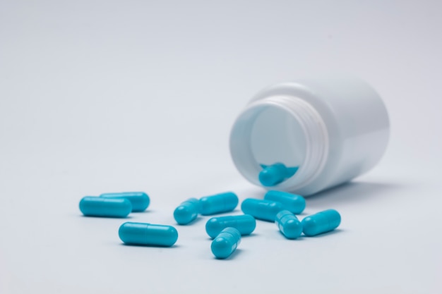 Capsules scattered from a bottle, on a white background.