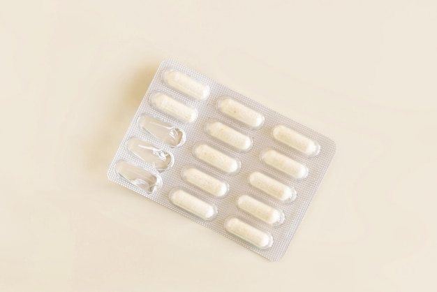 Capsules in a used plastic blister package on light beige top view Taking dietary supplements