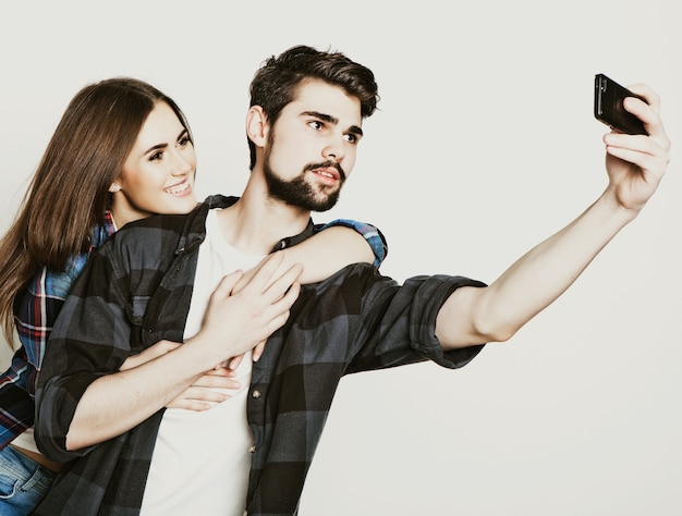 Capturing happy moments together. Happy young loving couple making selfie and smiling while standing against white background.Special Fashionable toning.