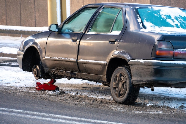 Car accident on the road in winter The driver changes the wheel on the road in the city in the cold in difficult conditions Dangerous road conditions in icy conditions