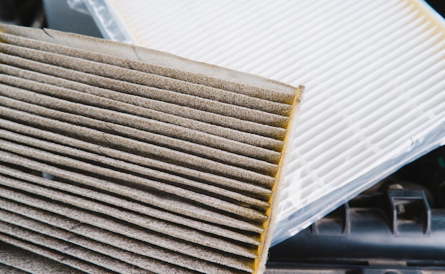 Car air filter clogged and new air filter in a plastic wrapped on background