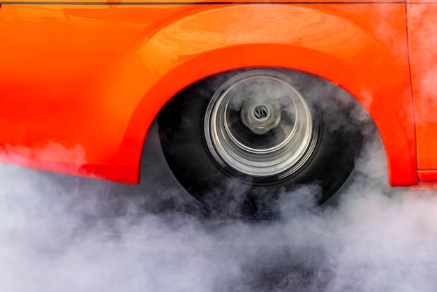 Photo car burnout wheels tire with white smokecar wheel burnout with smoke from the spinning tyre drag car