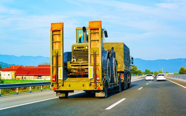 Car carrier transporter with tractors in road. Low tow Auto vehicles hauler on driveway. European transport logistics at haulage work transportation. Heavy haul trailer on highway.