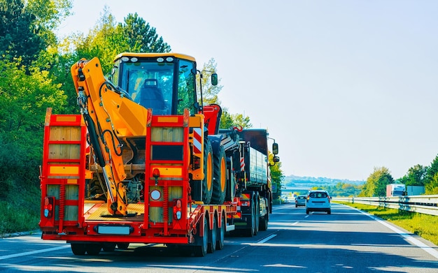 Car carrier transporter with tractors in road. Low tow Auto vehicles hauler on driveway. European transport logistics at haulage work transportation. Heavy haul trailer on highway.