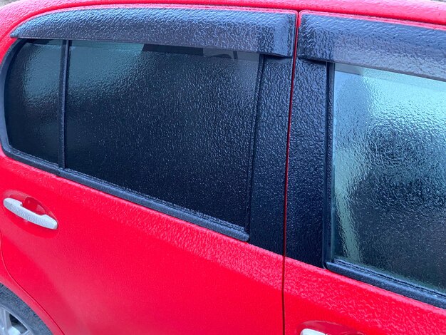 Car covered with ice close up Sparkling ice covered everything after ice storm cyclone and freezing rain Terrible beauty of nature concept Winter time Selective focus