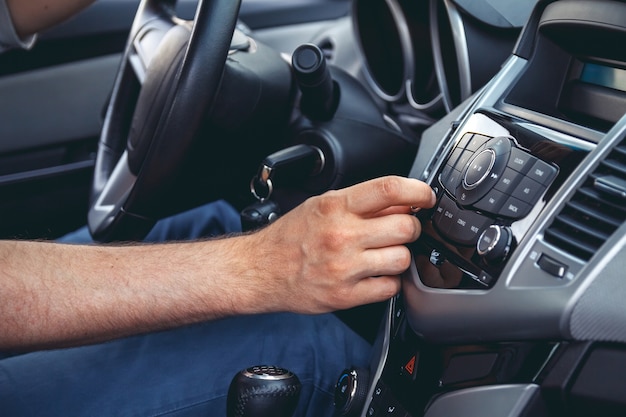 Car dashboard. Radio closeup. Man sets radio