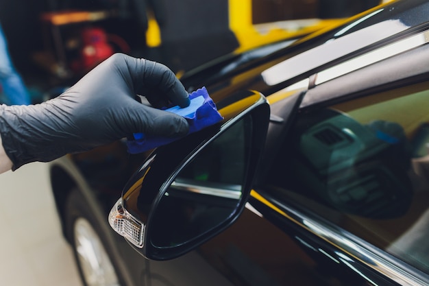 Photo car detailing - man applies nano protective coating to the car. selective focus.