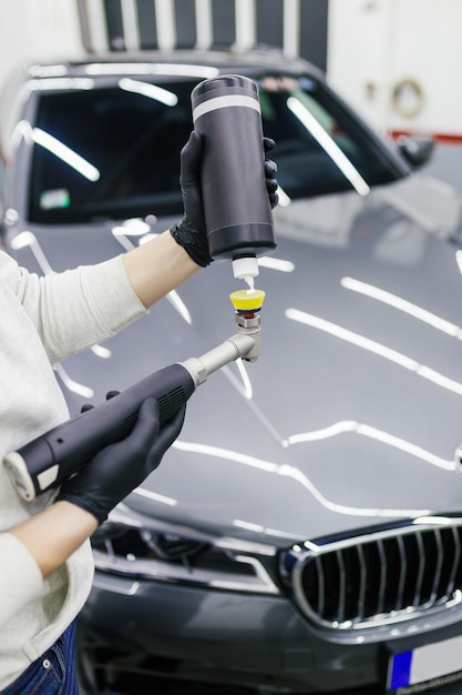 Car detailing - Worker with orbital polisher in auto repair shop. Selective focus.