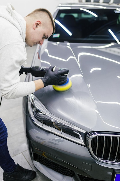 Car detailing - Worker with orbital polisher in auto repair shop.