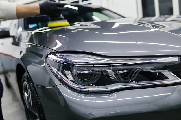 Car detailing - Worker with orbital polisher in auto repair shop.