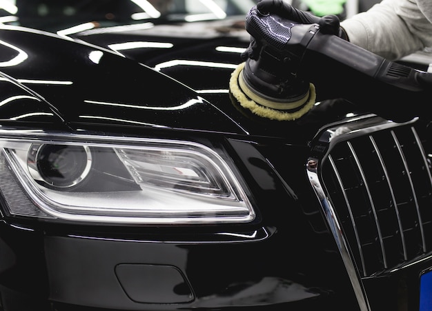 Car detailing - Worker with orbital polisher in auto repair shop.