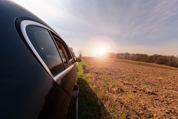 Photo car on a dirt road in a field of sunflowers and wheat with sunlight