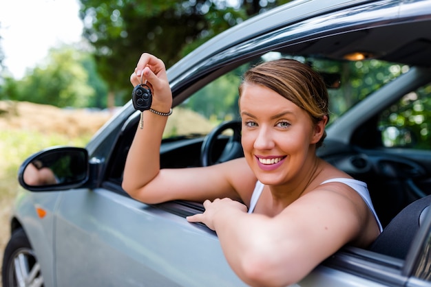 Car driver woman smiling showing new car keys and car