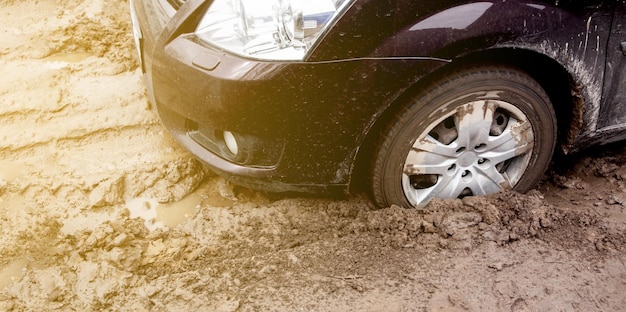 The car got stuck on a dirt road in the mud wheel of a car stuck in the mud on the road car on a dir