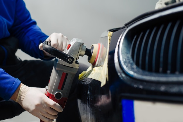 Car headlights cleaning with power buffer machine at car service