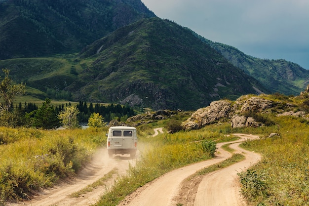 The car is moving forward along a dirt road among the mountains and hills. Mountain Altai.