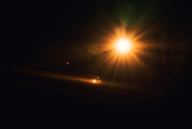 a car is visible on a dark night in the style of dark gold and light amber anamorphic lens flare