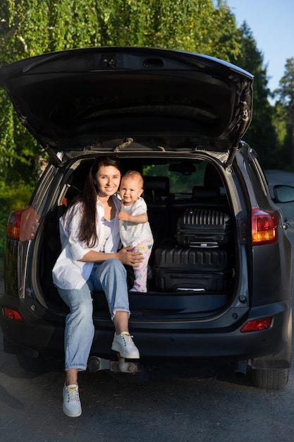 Car journey Travel with a child by car Mother and daughter sit in a car with an open trunk